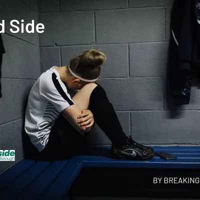 Breaking Barriers: Girl sitting on a changing room bench wearing sports clothes with her head in her knees. Text reads "Blind Side by Breaking Barriers"