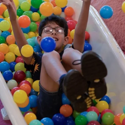 A child in a bath full of ballpit balls